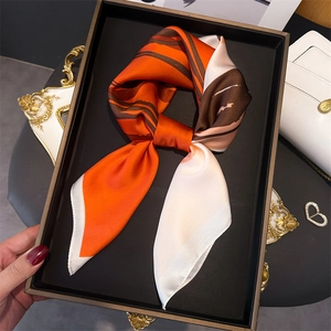 Detail of printed silk-like scarf with orange and brown abstract lines in a display tray