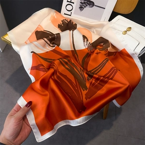 Detailed view of the smooth silk-like satin square scarf featuring orange floral print