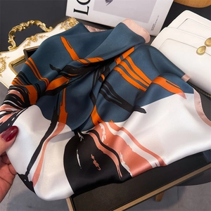 Detailed macro shot of abstract floral faux silk scarf draped over a white luxury handbag