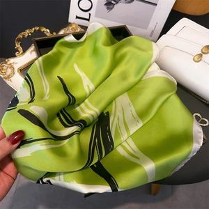 Detail shot of green and white abstract print silk scarf with fine rolled edges and glossy finish