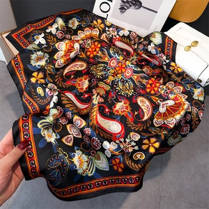 Vue détaillée d'un foulard carré en soie avec des motifs ethniques paisley colorés sur noir