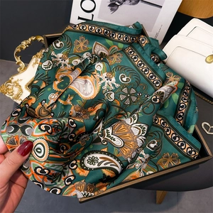 Détail d'un foulard en soie vert foncé avec motif paisley et texture satinée brillante