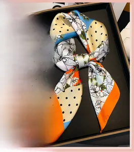 Détail d'un foulard en soie à imprimé floral avec des motifs élégants bleus et oranges