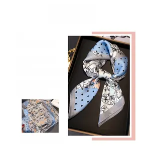 Détail d'un carré de soie imprimé avec motifs floraux bleus et bordure grise élégante