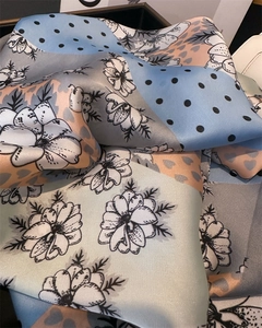 Détail d'un foulard en satin de soie montrant des motifs floraux et des pois délicats
