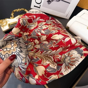 Detail of red floral satin scarf featuring retro palm leaf print and silky glossy texture