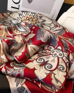 Detailed close-up of ethnic floral pattern on red and beige silk satin neck scarf