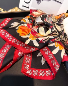 Detailed close-up of floral silk scarf with fine rolled edges on a luxury display tray