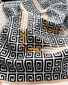 Dettaglio di un lussuoso foulard in seta con motivo a G geometrico e stampa a catena dorata