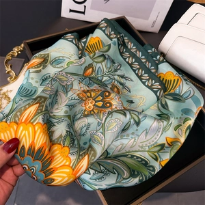 Detail of teal faux silk floral scarf featuring orange blossoms and elegant paisley patterns