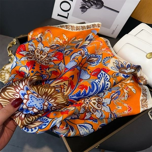 Close-up of luxury floral silk scarf in vibrant orange and royal blue bohemian pattern