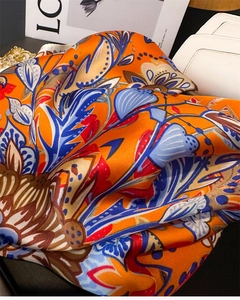 Macro detail of vibrant orange floral print silk scarf with intricate vintage patterns