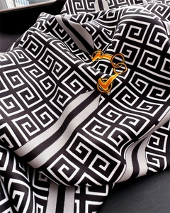 Dettaglio di un foulard in seta di lusso con motivo 4G e decorazioni a catena dorata