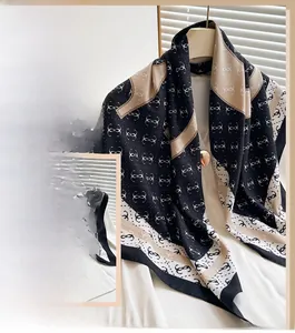 Detailed macro view of high-quality imitation silk scarf with monogram print and contrast borders