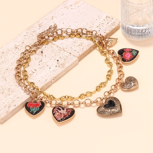 Détail d'un collier à plusieurs rangs avec pendentifs cœur en émail fleuri et métal gravé