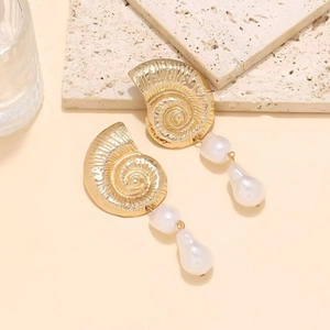 Orecchini pendenti a conchiglia vintage con perle finte su sfondo di pietra naturale