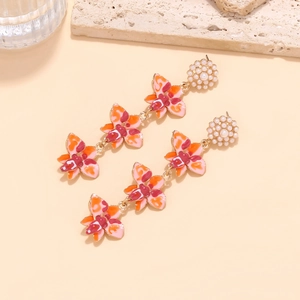 Vue détaillée de boucles d'oreilles à pompons avec fleurs en émail et perles fines