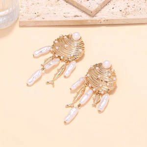 Détail de boucles d'oreilles coquillage dorées avec perles baroques et charms poissons