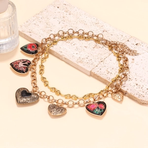 Détail du collier doré à plusieurs rangs avec pendentifs cœurs en émail rouge sur pierre
