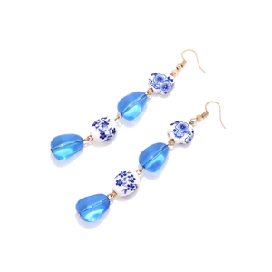 Detail of long blue resin beads and blue floral ceramic drop earrings with gold hooks