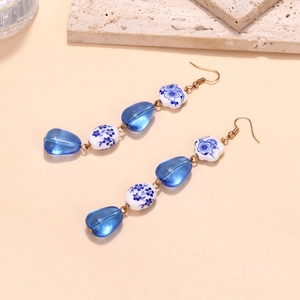 Detail of drop earrings with blue resin and porcelain beads on a stone display