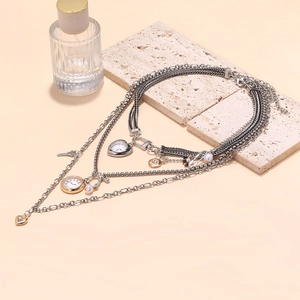 Multi-layer vintage necklace with pocket watch, heart, and key charms on stone display