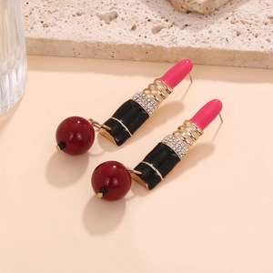 Detailed macro view of lipstick-shaped enamel earrings with sparkling rhinestones