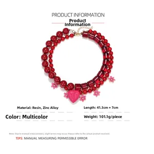 Detail view of double-layer beaded necklace with pink heart and floral pendant charms