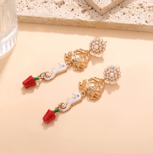 Macro detail of gold sea horse, crab and tulip enamel drop earrings with pearls