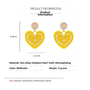 Detail view of yellow heart earrings with lemon motif and faux pearl flower studs