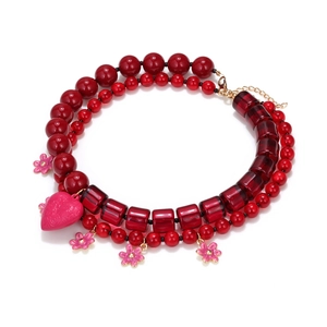 Beaded layered necklace with pink heart and flower charms on white background