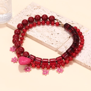 Handmade beaded layered necklace with red beads and pink heart floral pendants on stone