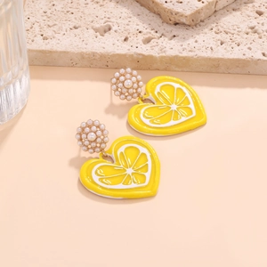 Detail of heart earrings with lemon enamel design and white pearls on golden base