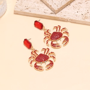 Golden crab drop earrings with red crystals and rectangular gemstones on a stone base
