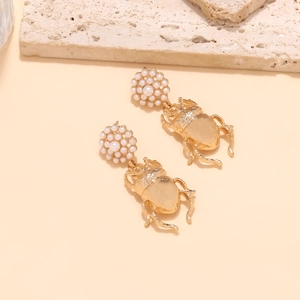 Vue détaillée des boucles d'oreilles scarabée dorées avec clous en perles élégants