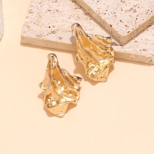 Vintage abstract geometric earrings with golden crumpled texture on travertine stone