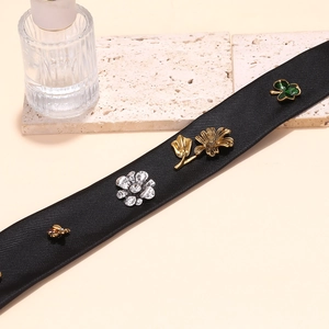 Tie necklace with bee flower clover charms on black twill strap in minimalist setting