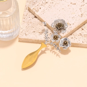Détail de la broche fleur vintage en argent avec vase doré sur socle en pierre