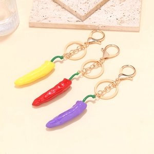 Close-up of three colorful resin chili pendants with golden keychains in a stylish set