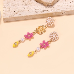 Macro shot of asymmetric flower earrings with pink enamel and yellow lemon drop detail