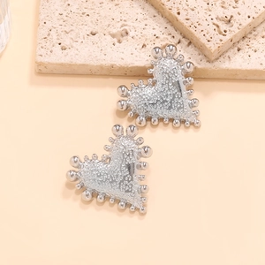 Macro shot of silver heart studs with beaded edges and unique textured finish