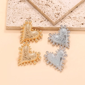 Detailed view of heart stud earrings with vintage beaded edges and lava texture finish