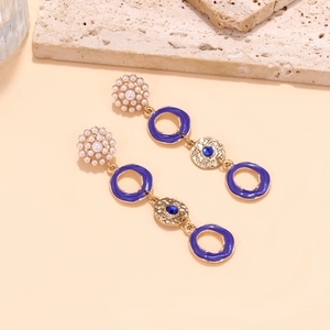 Detailed shot of long enamel drop earrings with pearl flower and navy blue round pendants