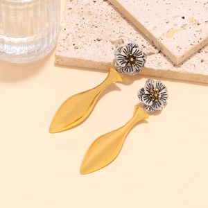 Detailed close-up of vintage-style silver flower studs and gold water drop pendants