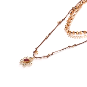 Macro shot of multi-layer beaded necklace with golden flower pendant and amber crystals