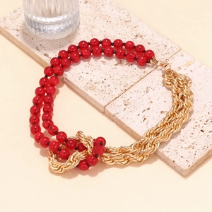 Detail of red bead and gold twisted chain necklace on natural stone display