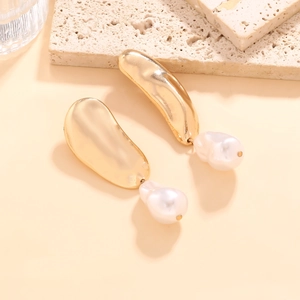 Vintage gold asymmetric geometric earrings with baroque pearls on a stone background