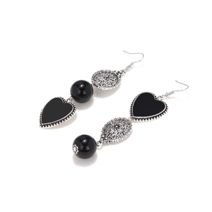 Detail of vintage heart earrings with silver filigree and black heart pendant