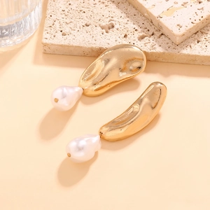 Detailed close-up of golden irregular textured earrings with unique baroque pearl drops
