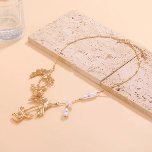 Collana di perle barocche e fiori in lega dorata su una pietra chiara